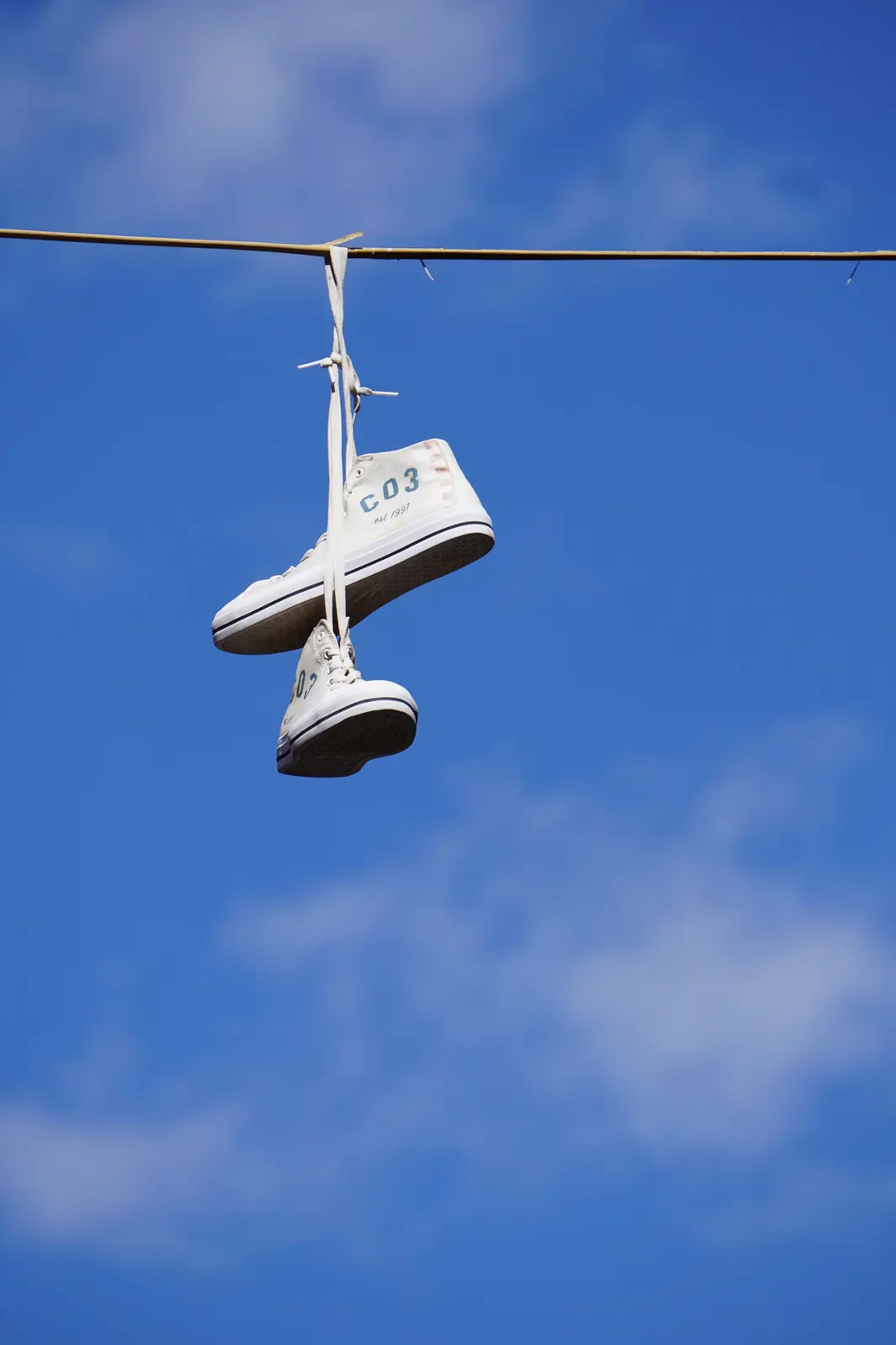 Pair of shoes hanging against a blue sky