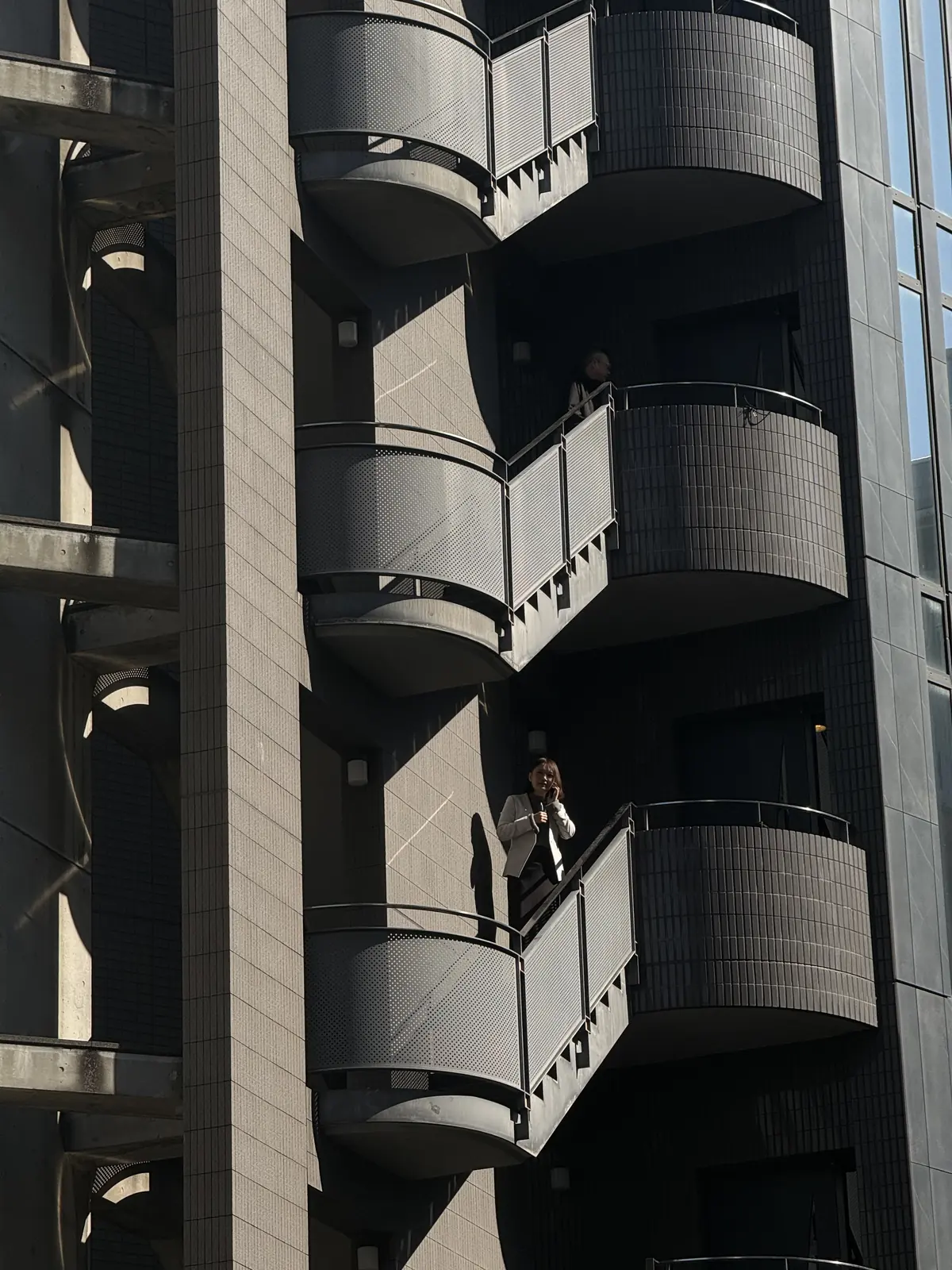 Person standing on a curved apartment balcony