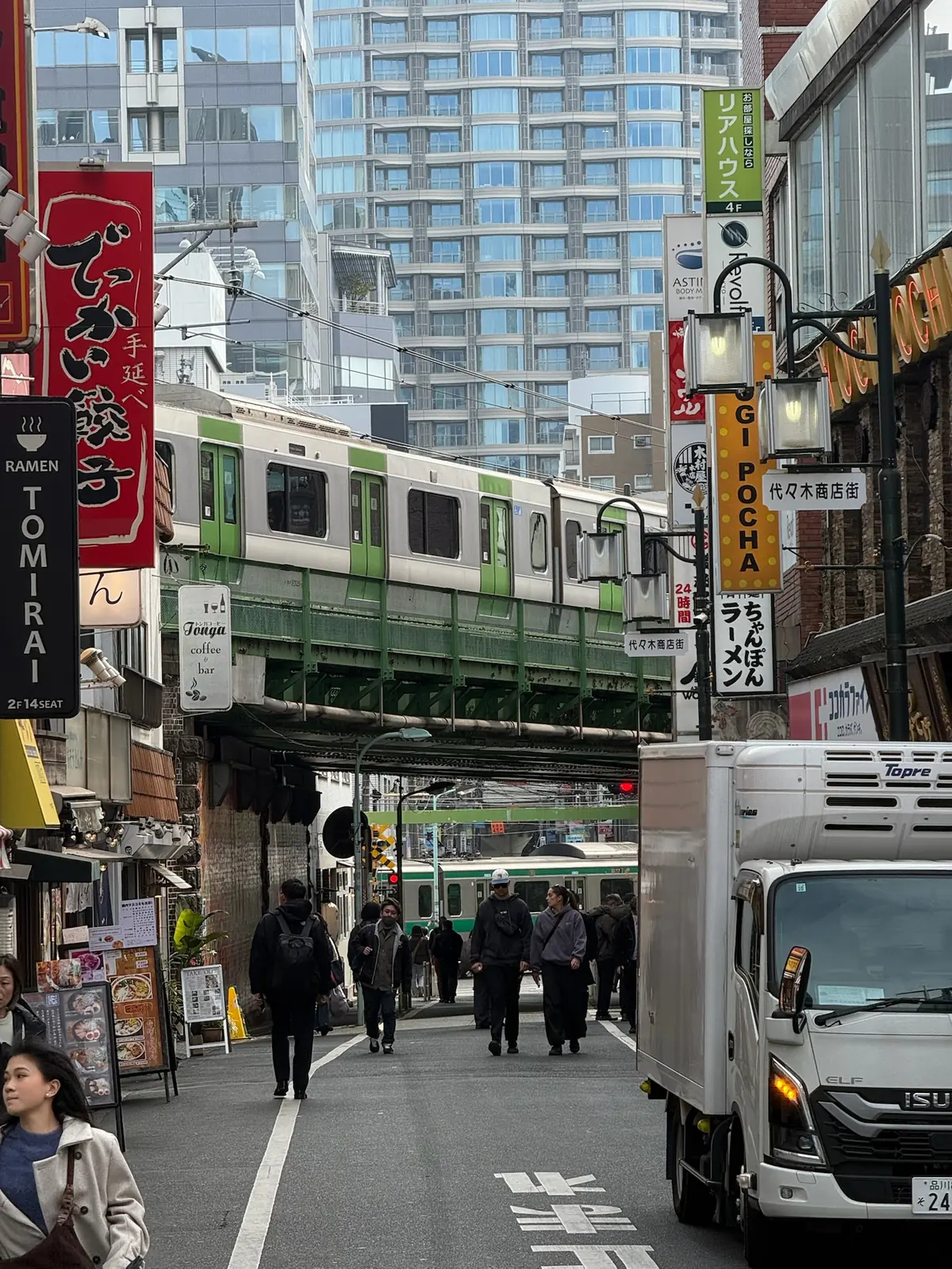 Green train passing through a busy neighbourhood