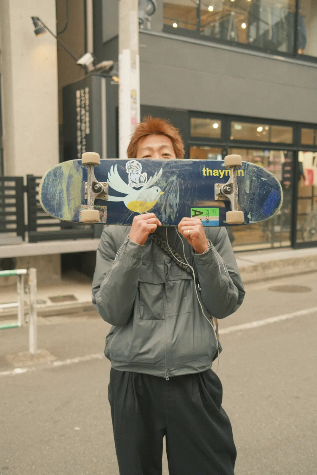 Person holding a skateboard in front of their face
