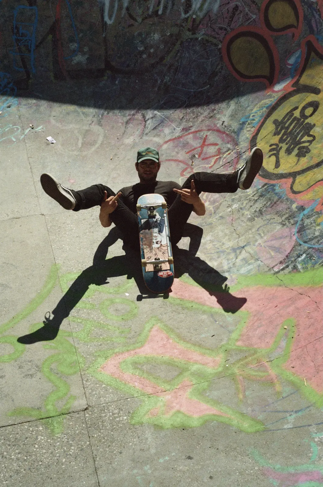 Skateboarder posing in front of a painted mural